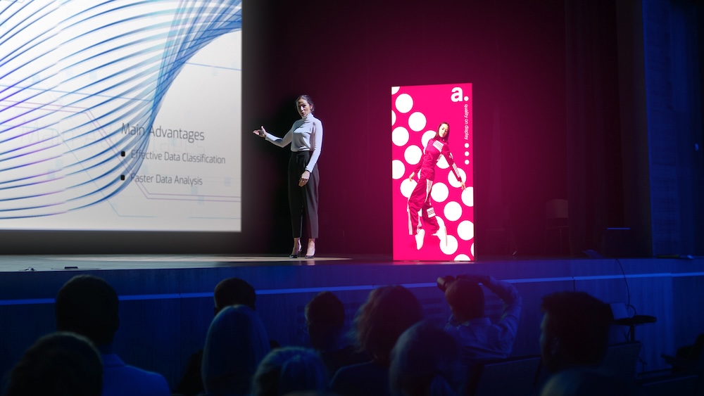 Prezenterka konferencji z kasetonem w tle